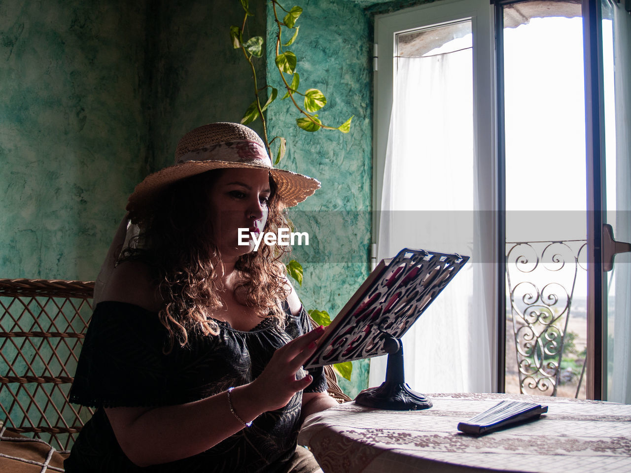 Woman reading book on table at home