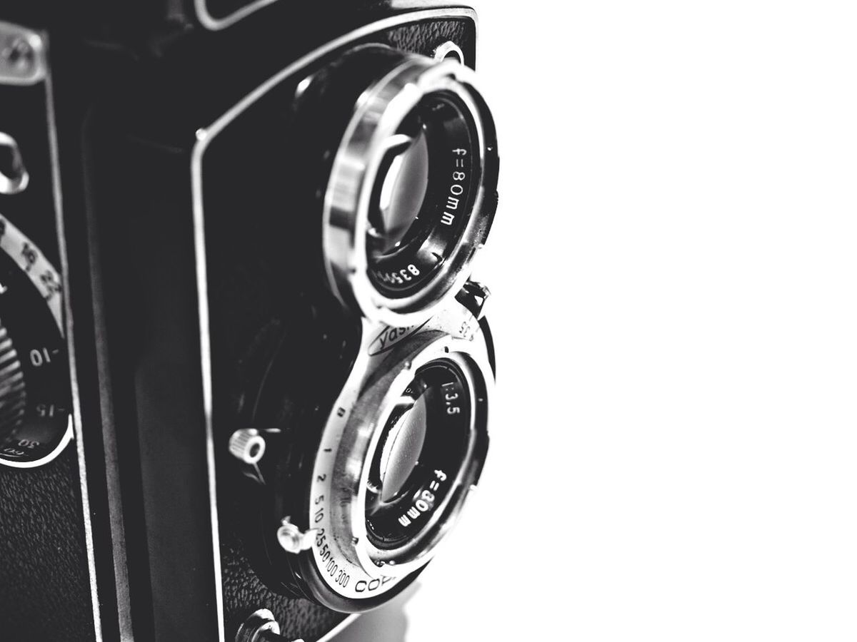 CLOSE-UP OF VINTAGE CAMERA ON WHITE WALL