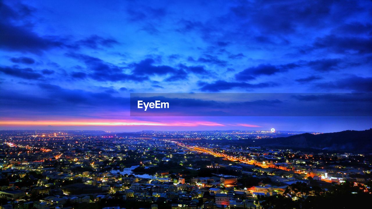 High angle view of illuminated cityscape against sky at dusk