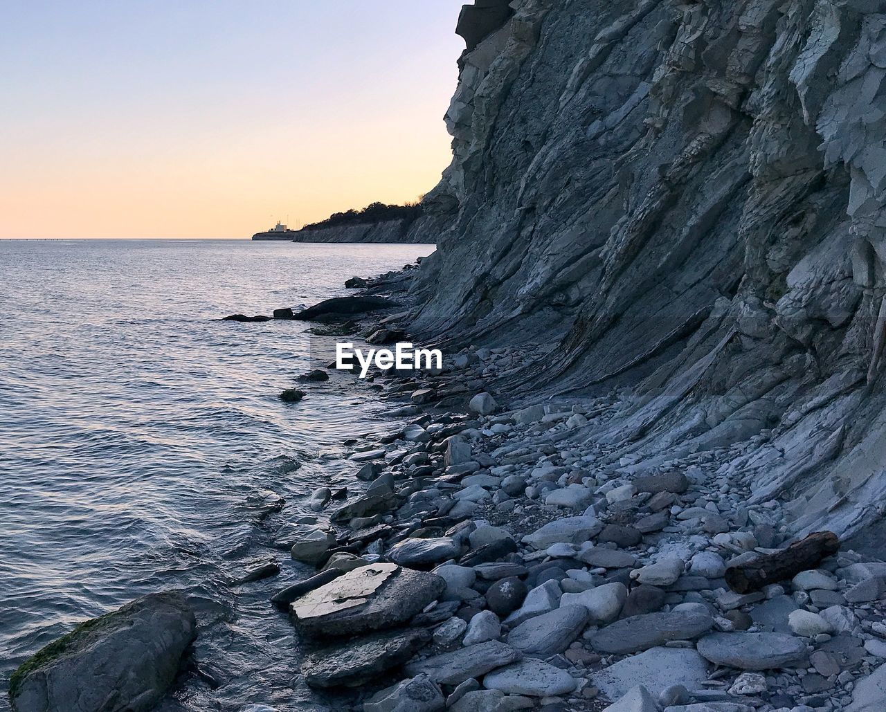 Rock formation on beach against sky during sunset