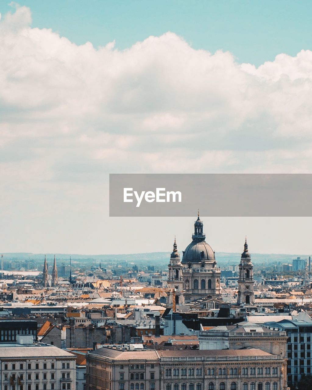 Aerial view of cityscape against cloudy sky during sunny day