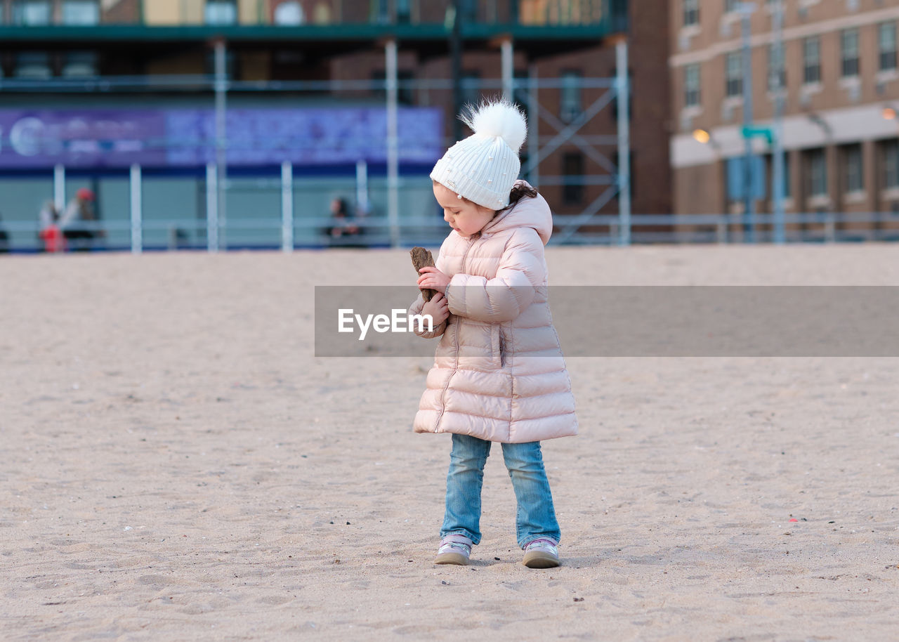 Little girl is playing on an empty beach on a cold day