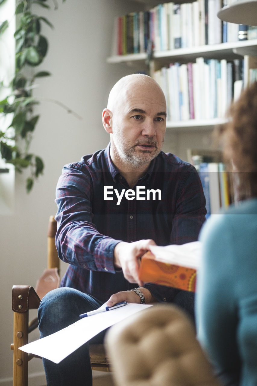 Male therapist giving tissue to female patient during therapy session