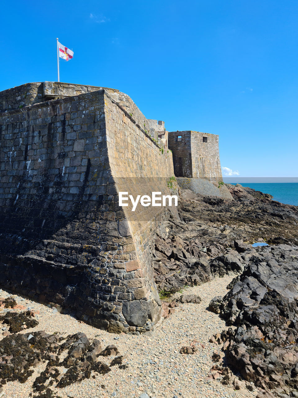 STONE WALL BY SEA AGAINST SKY