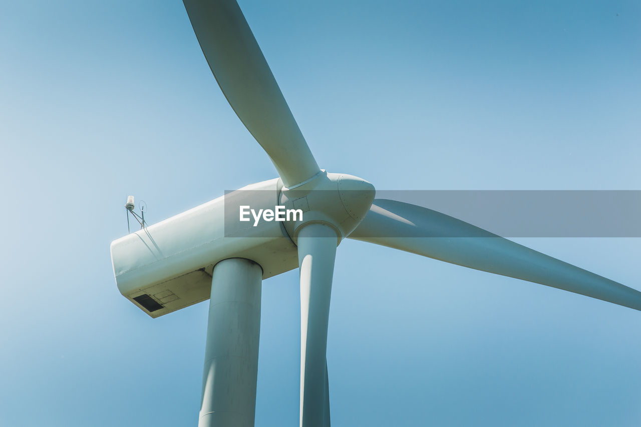 Low angle view of wind turbine against clear blue sky