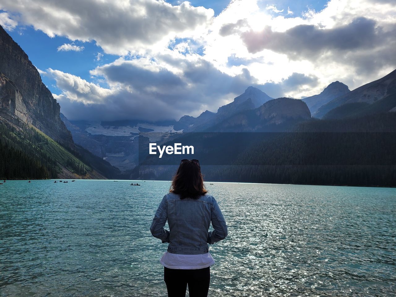 rear view of man standing by lake against mountain