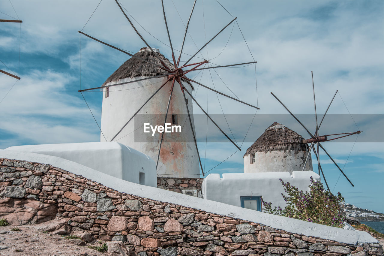 LOW ANGLE VIEW OF TRADITIONAL WINDMILL AND BUILDING AGAINST SKY