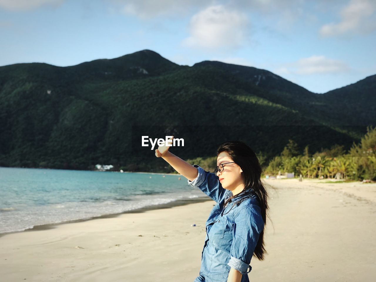 Young woman standing on beach against sky