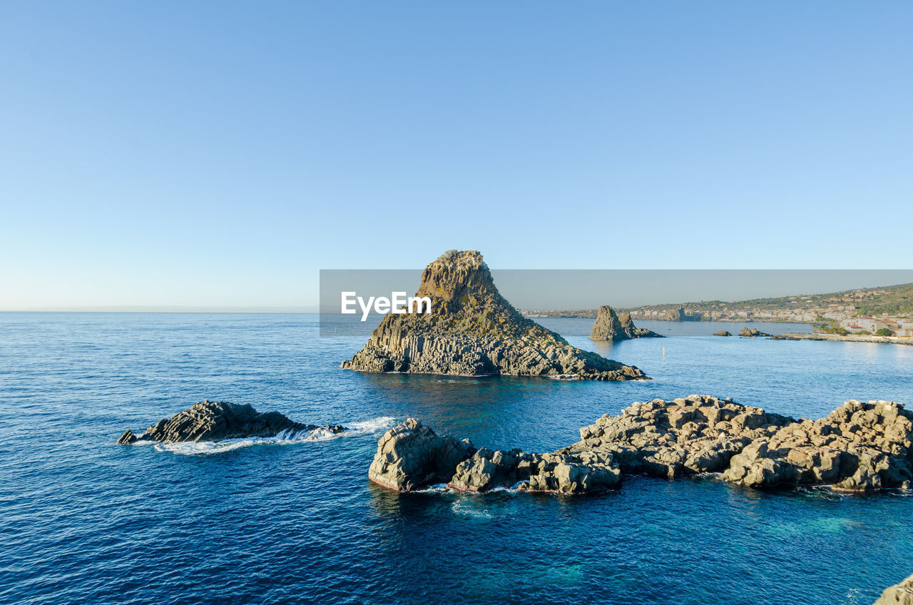 ROCK FORMATION IN SEA AGAINST CLEAR SKY