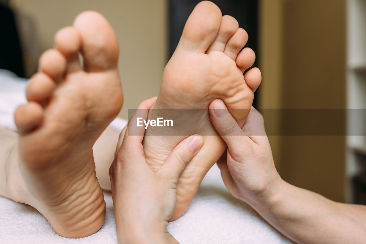 The masseur gives a massage to the female feet at the spa.