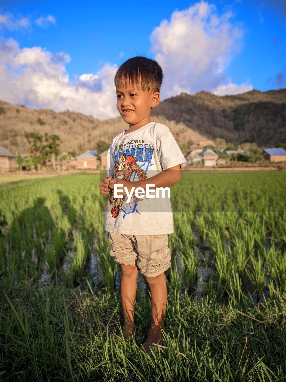 childhood, child, one person, grass, men, nature, field, plant, land, sky, landscape, meadow, standing, full length, casual clothing, toddler, smiling, portrait, cute, agriculture, grassland, emotion, cloud, front view, happiness, day, rural scene, person, vacation, leisure activity, outdoors, environment, innocence, natural environment, looking at camera, mountain, rural area, growth, shorts, summer, beauty in nature, lifestyles, blue