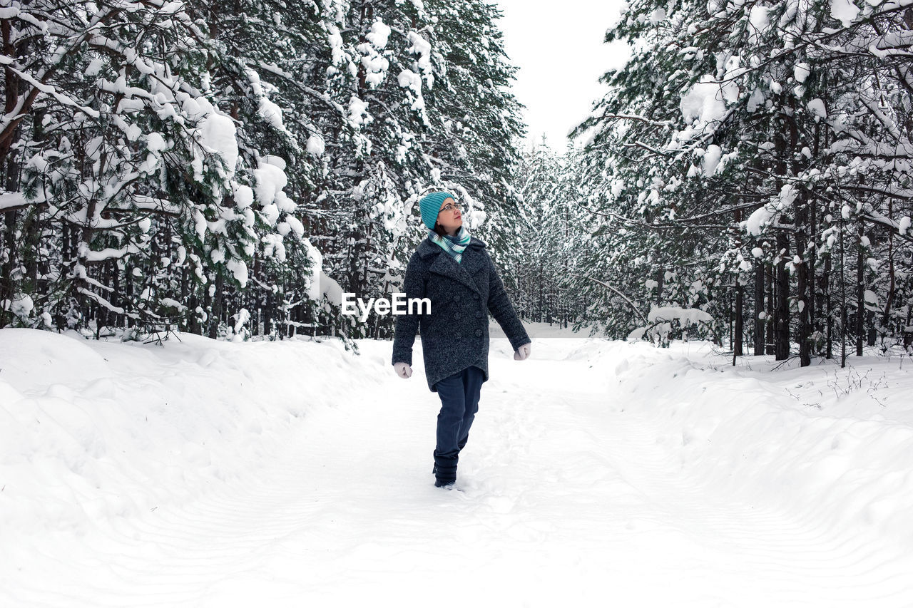 A woman is walking in the winter snowy forest.