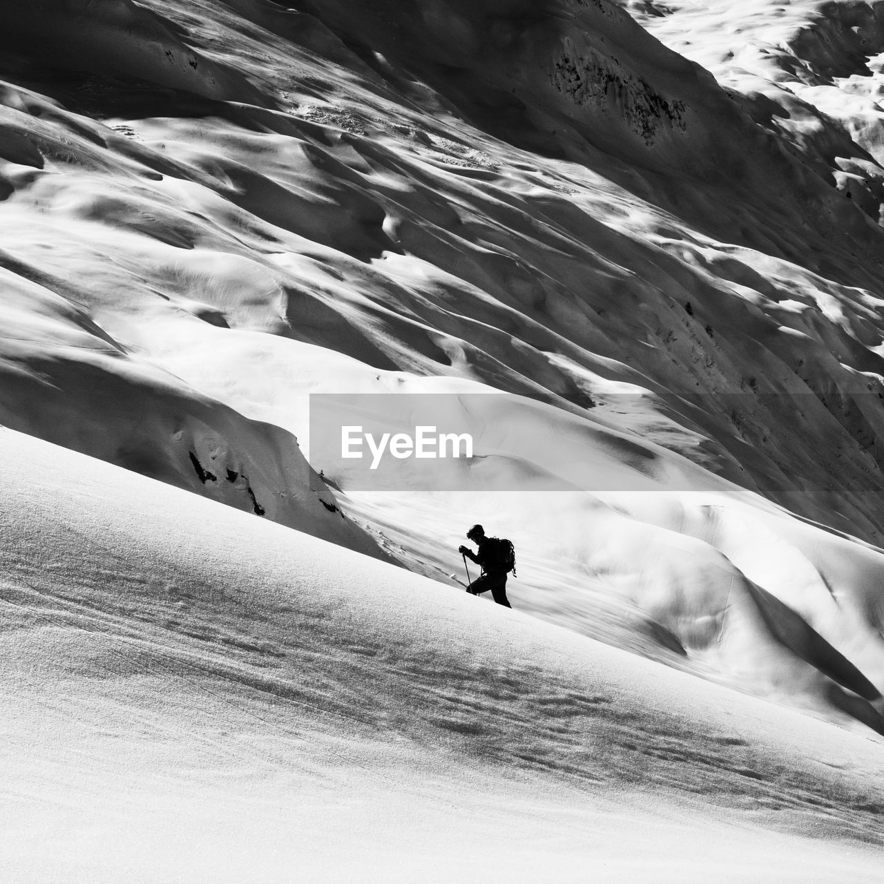 Silhouette of ski touring person ascending a snowcapped mountain