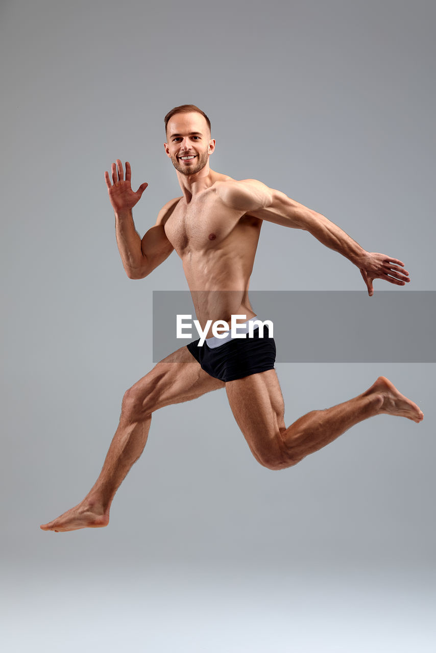 low angle view of man with arms raised standing against gray background