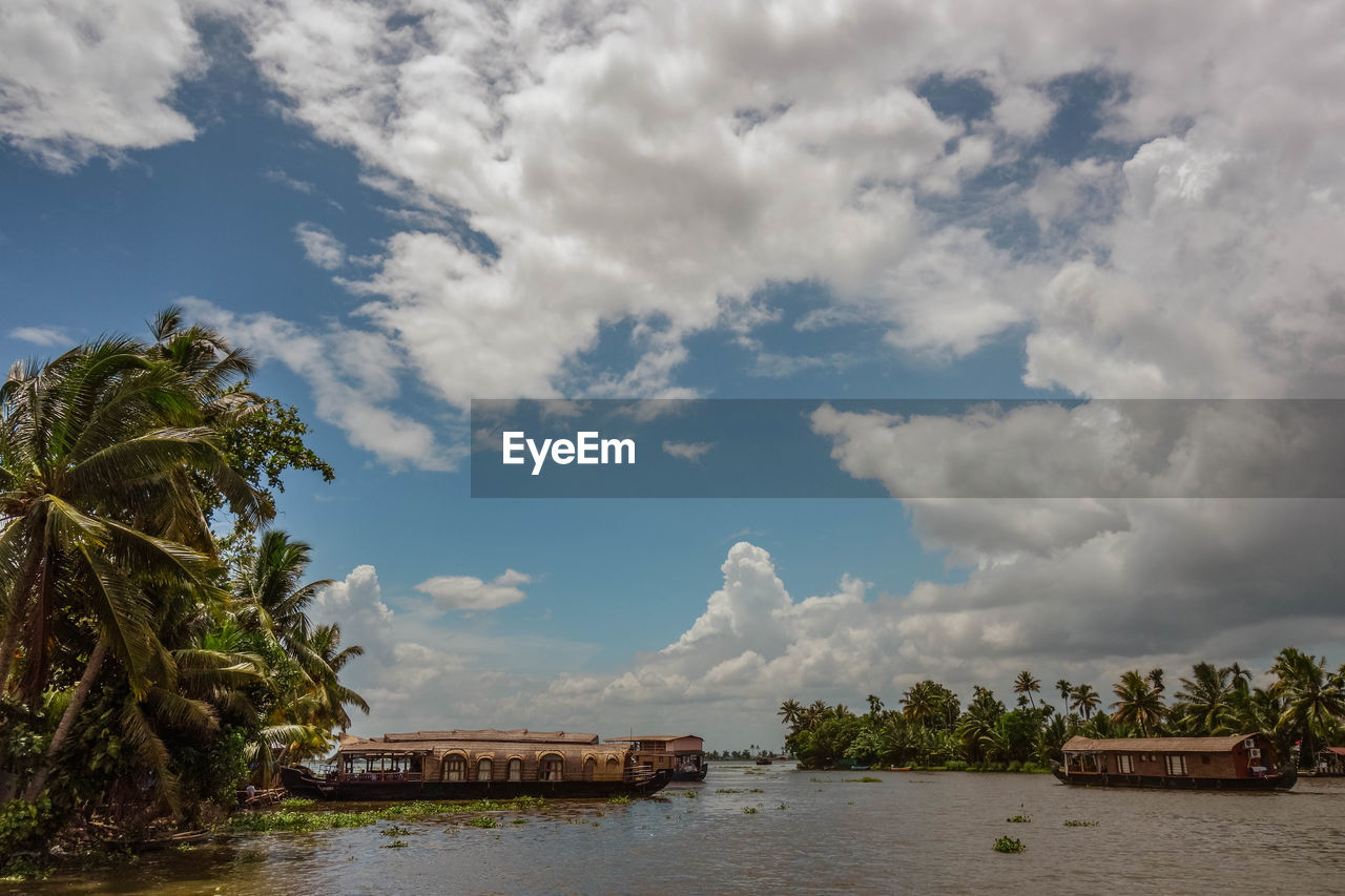 Boathouses in backwaters against cloudy sky