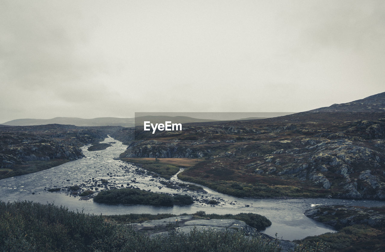 Scenic view of river by mountains against sky