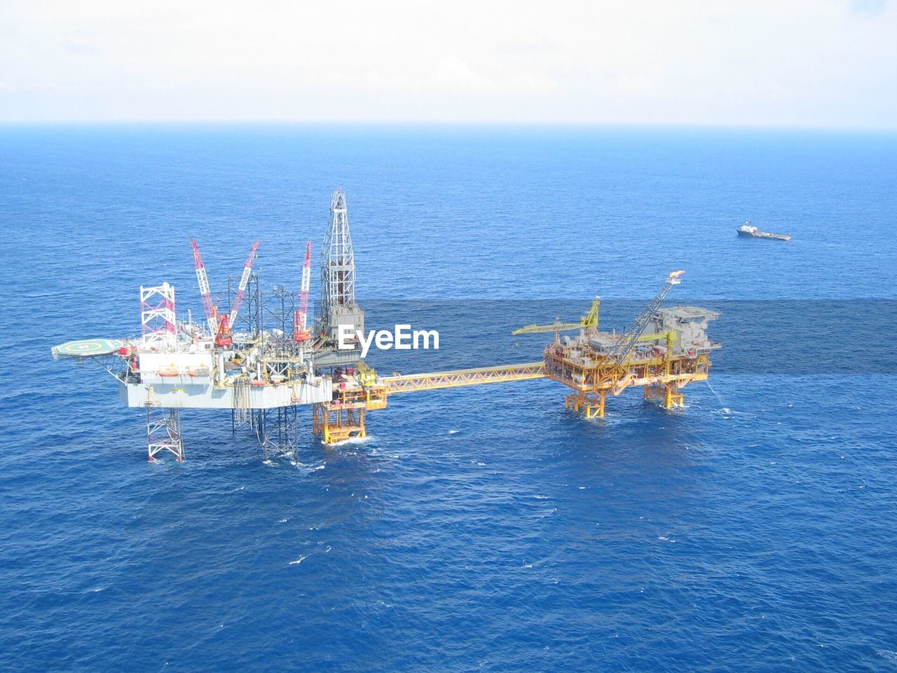 Scenic view of oil drill in sea against clear sky