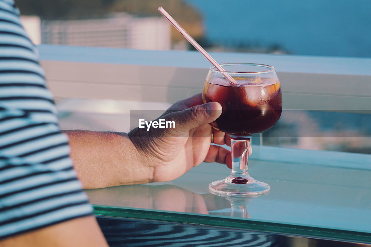 Close-up of hand holding drink on table