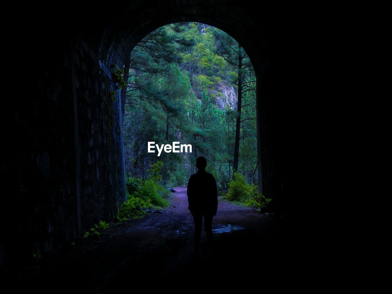 SILHOUETTE MAN STANDING IN TUNNEL