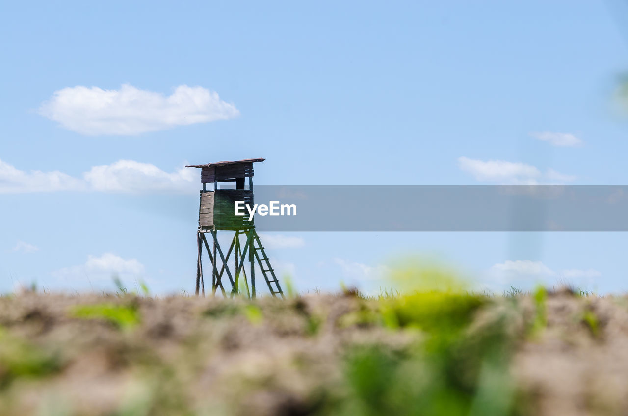 Hunting tower on a field against sky