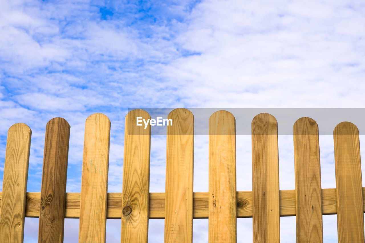 CLOSE-UP OF WOODEN POSTS AGAINST SKY