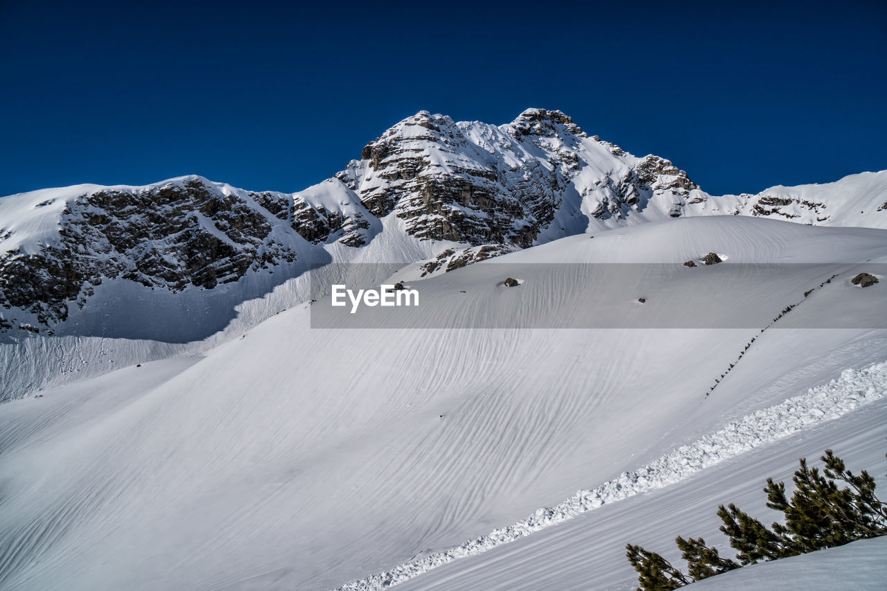 Scenic view of snow covered mountains against blue sky