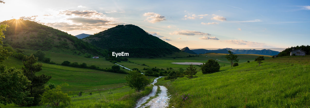 environment, landscape, nature, scenics - nature, sky, land, mountain range, mountain, plant, beauty in nature, valley, cloud, highland, meadow, grass, rural scene, field, sunset, rural area, green, tranquility, tree, sun, panoramic, travel, water, plateau, grassland, no people, tranquil scene, agriculture, environmental conservation, sunlight, travel destinations, summer, forest, social issues, idyllic, plain, non-urban scene, outdoors, sunbeam, road, wilderness, tourism, blue, lake, mountain peak, farm, ridge, activity, springtime, pasture, mountain pass, twilight, architecture, building, fog, vacation, holiday, multi colored