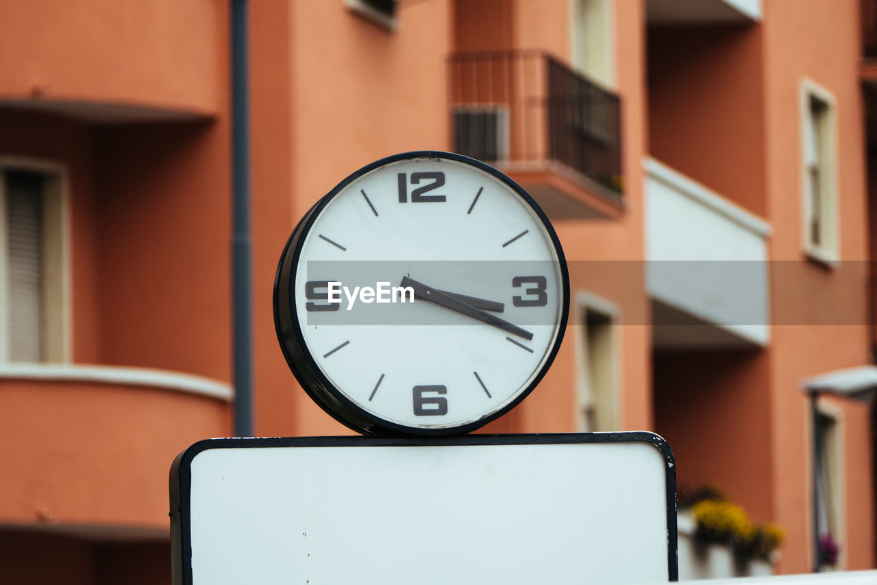 Clock against building in city