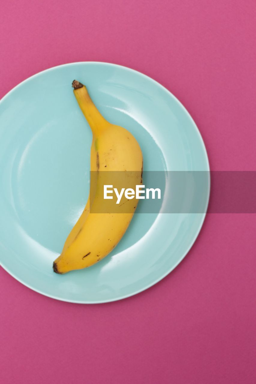 Banana in a blue plate on pink background
