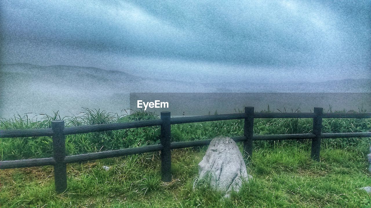 SCENIC VIEW OF GRASSY FIELD AGAINST STORM CLOUDS