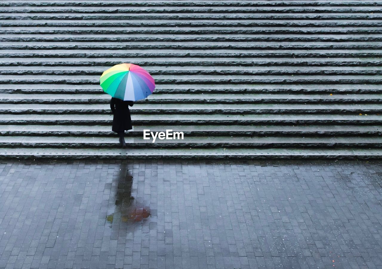 High angle view of woman walking with umbrella