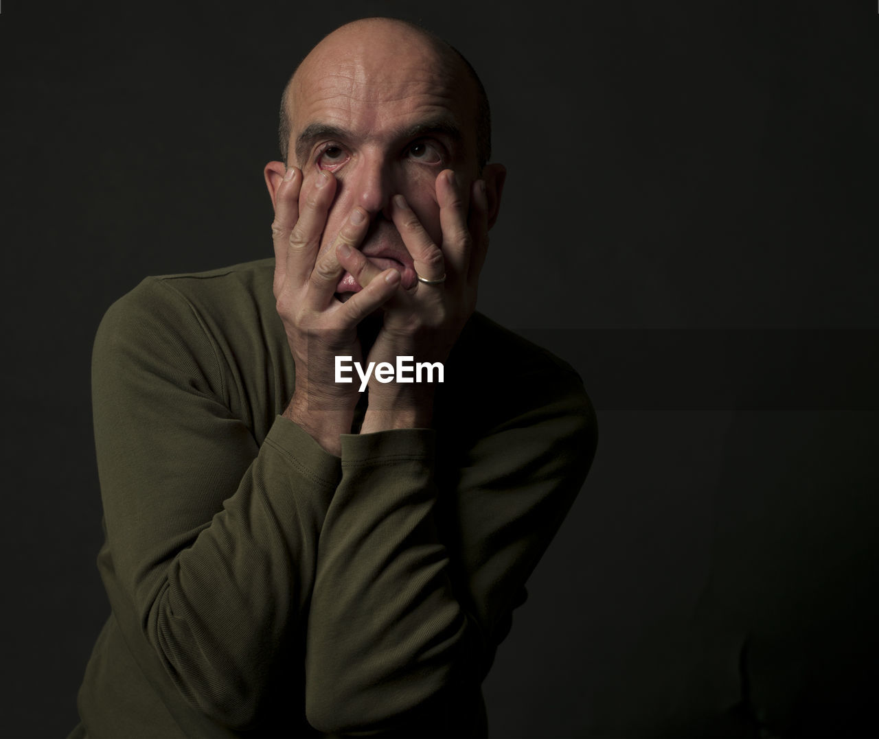 Portrait of man making face against black background