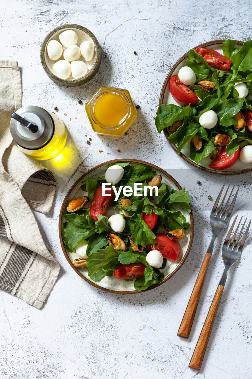 Healthy diet salad with arugula, mozzarella, mussels and vinaigrette dressing. 