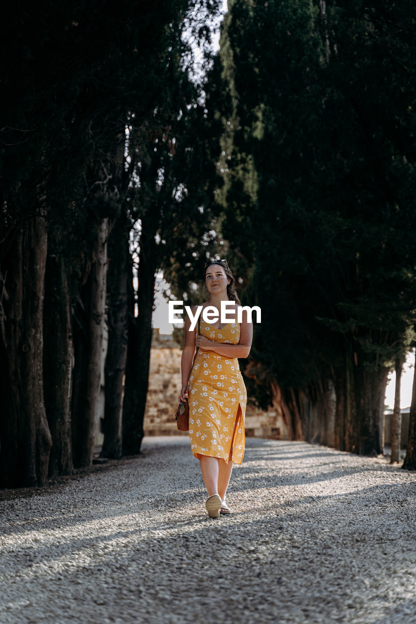 rear view of woman walking on road in forest