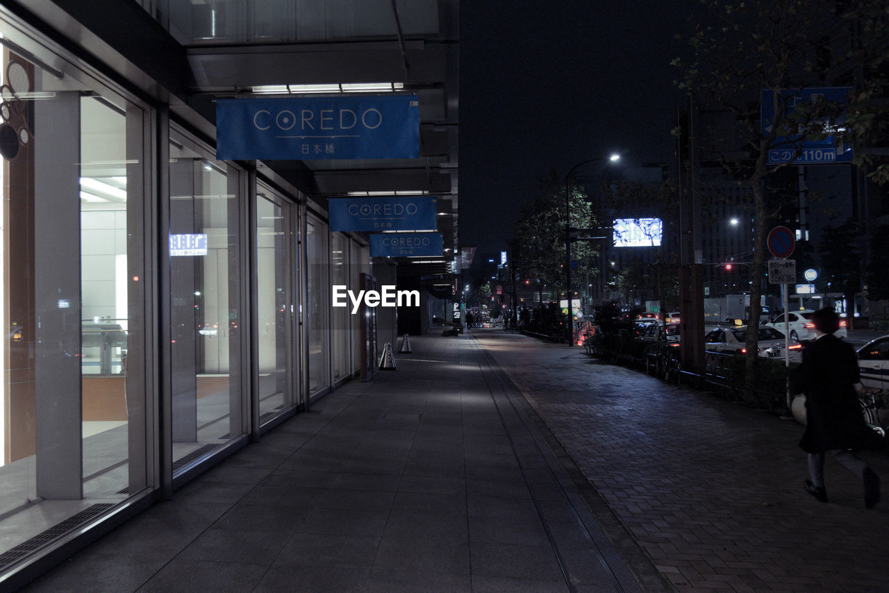 ILLUMINATED STREET AMIDST BUILDINGS IN CITY