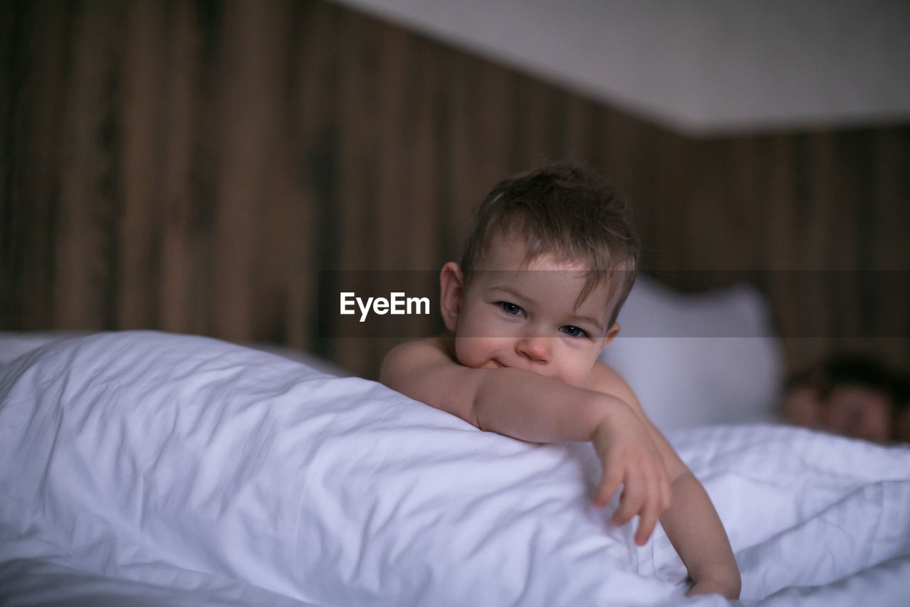 Close-up of cute baby boy lying on bed at home