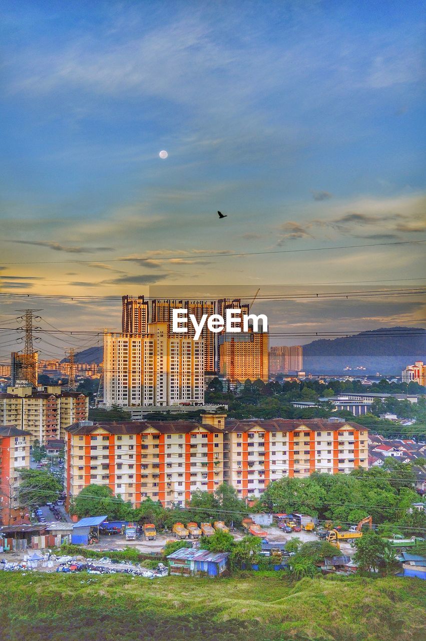 HIGH ANGLE VIEW OF BUILDINGS AGAINST CLOUDY SKY DURING SUNSET