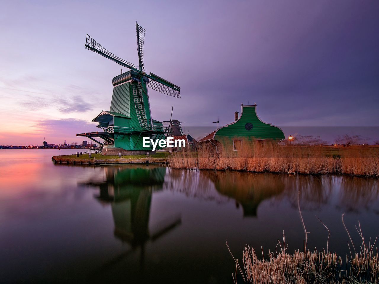 Windmill by calm lake against sky during sunset at zaanse schans
