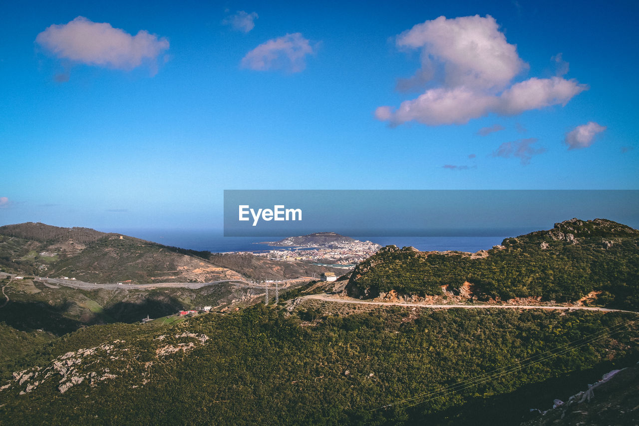 Scenic view of sea and mountains against blue sky