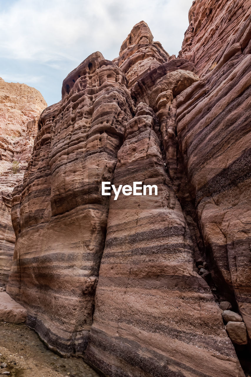 rock, rock formation, arch, travel destinations, landscape, environment, nature, scenics - nature, geology, travel, sky, beauty in nature, non-urban scene, land, cloud, canyon, desert, wadi, no people, terrain, eroded, sandstone, valley, cliff, formation, physical geography, outdoors, tranquility, climate, mountain, ancient history, day, tourism, extreme terrain, layered, arid climate, tranquil scene