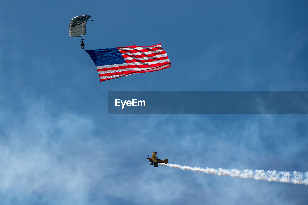 Low angle view of sky diver and airplane flying against sky