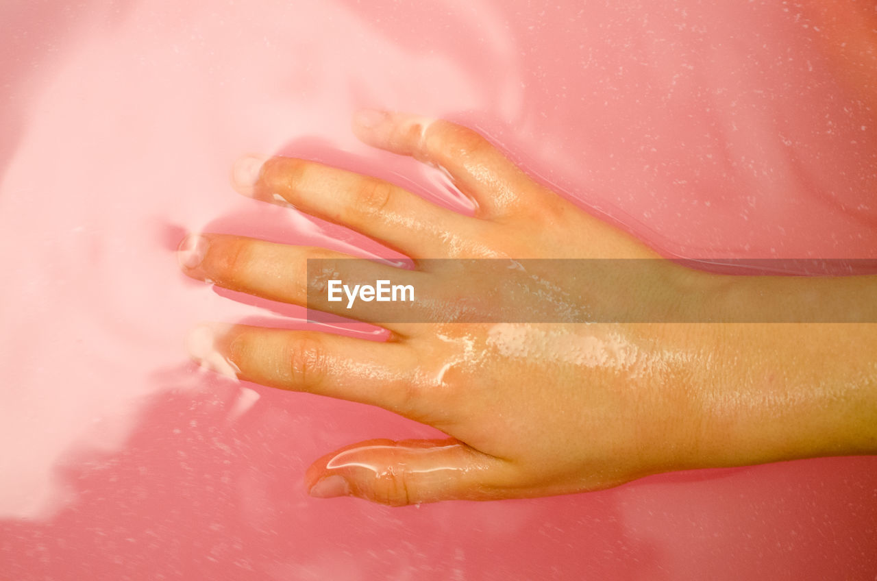 Cropped hand of boy in pink liquid