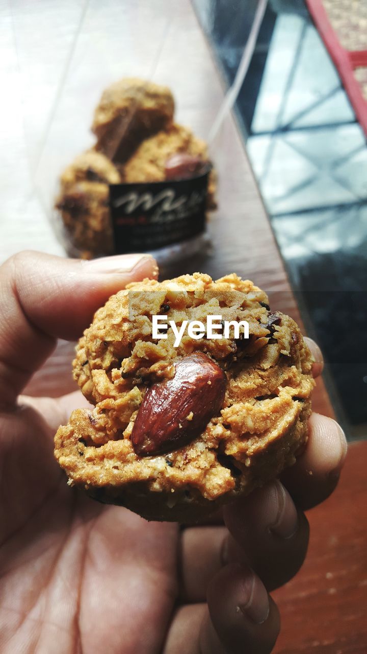 Cropped hand holding cookie at home