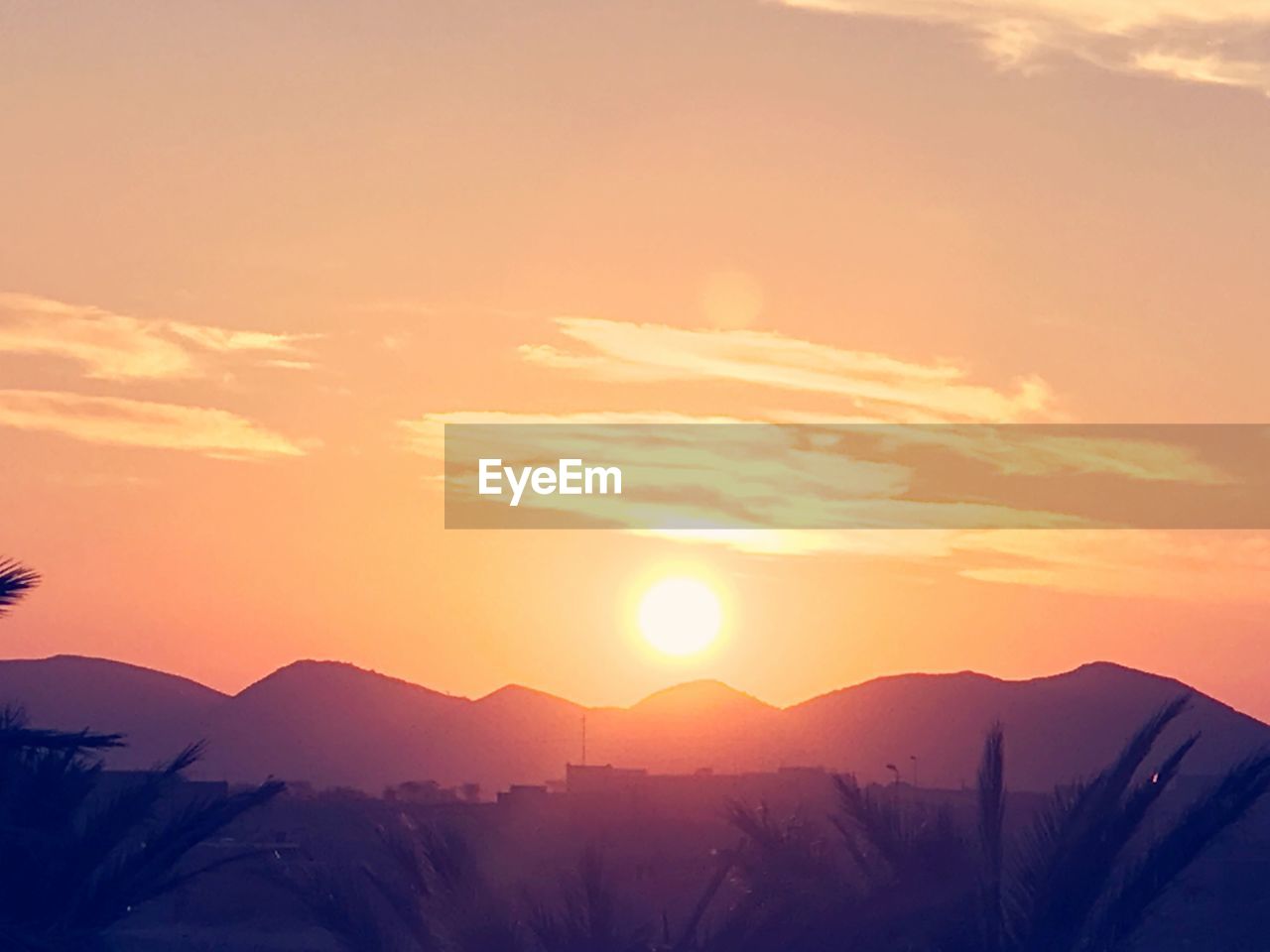 SCENIC VIEW OF SILHOUETTE MOUNTAINS AGAINST ORANGE SKY