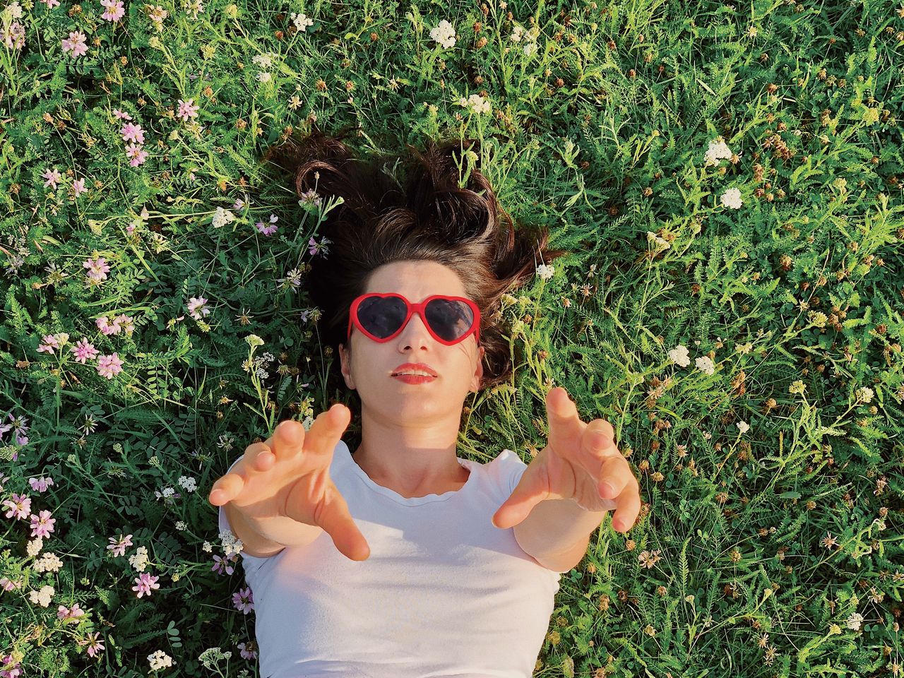 Portrait of woman wearing sunglasses lying on grassy land