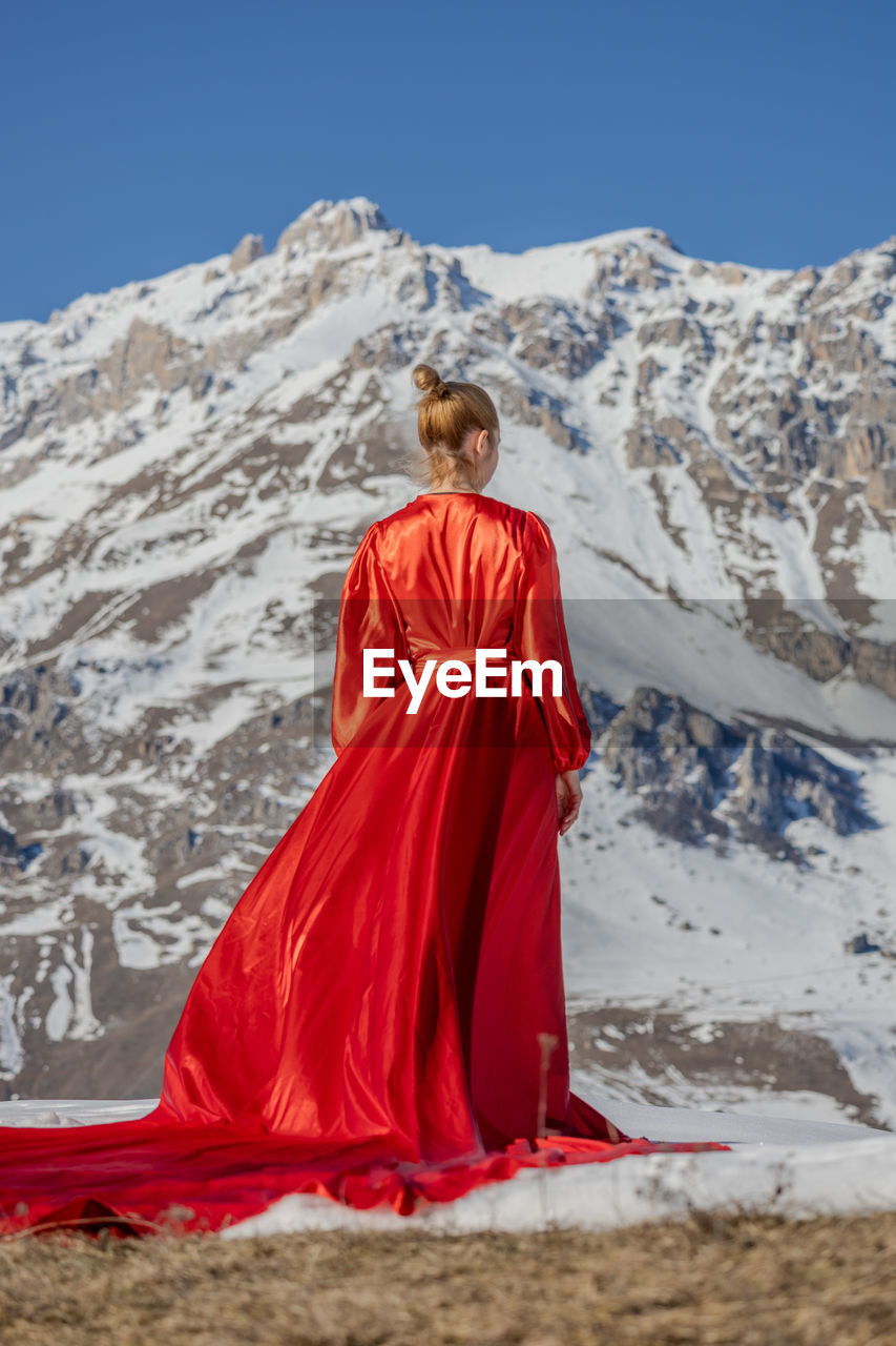 Rear view of woman standing on snowcapped mountain