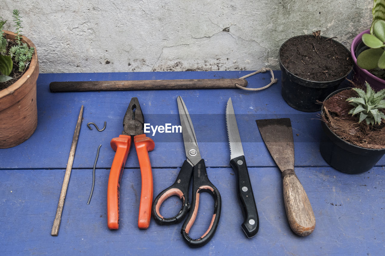 High angle view of gardening equipment amidst potted plants