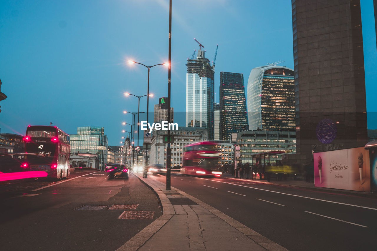 VIEW OF CITY STREET AND BUILDINGS AGAINST SKY IN BACKGROUND