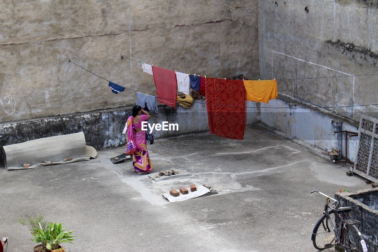 Rear view of woman removing clothes from rope