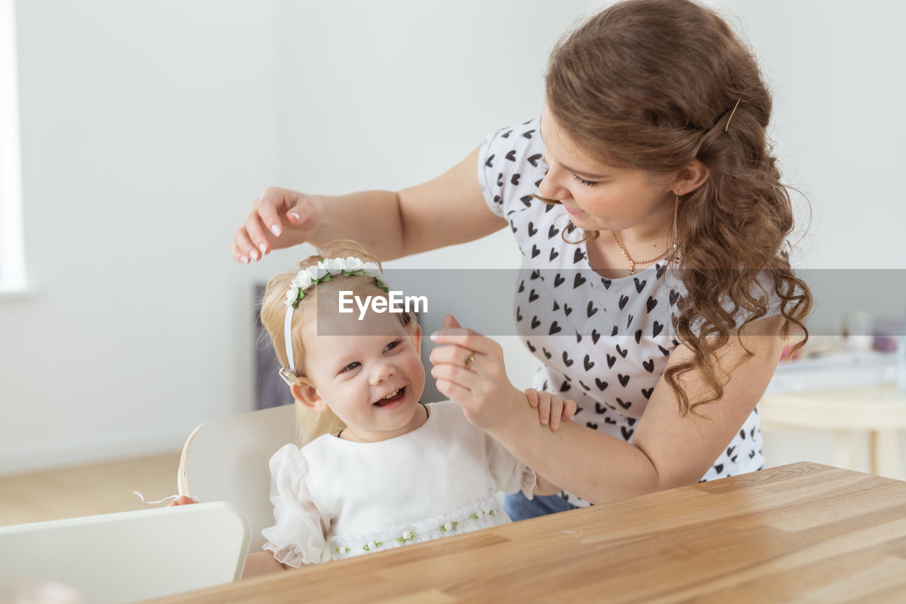 side view of mother and daughter sitting on table